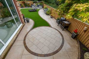 Patio, steps, artificial grass & landscaping by Stow Construction & Landscaping in Smithycroft, Hamilton 2018 using Marshalls Symphony Vitrified Buff, Drivesett Savannah Autumn, Fairstone Sawn Versuro bull-nosed steps Golden Sand, Fairstone walling Autumn Bronze, Evergreen Village Green 30mm artificial grass.